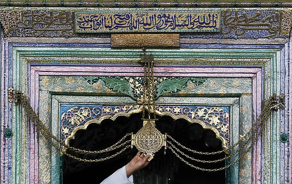 Kashmiri man touches chain tied to gate of shrine during Ramadan in Srinagar