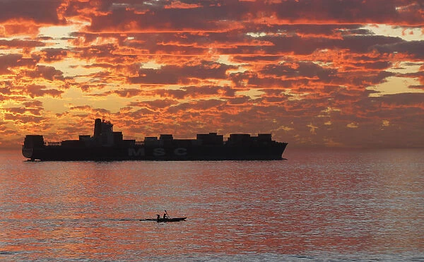 Kayakers take in the last of the days light as they paddle past a ship anchored off
