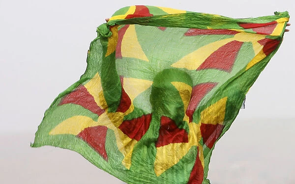A Kurdish man waves a scarf painted with traditional Kurdish colours during a rally