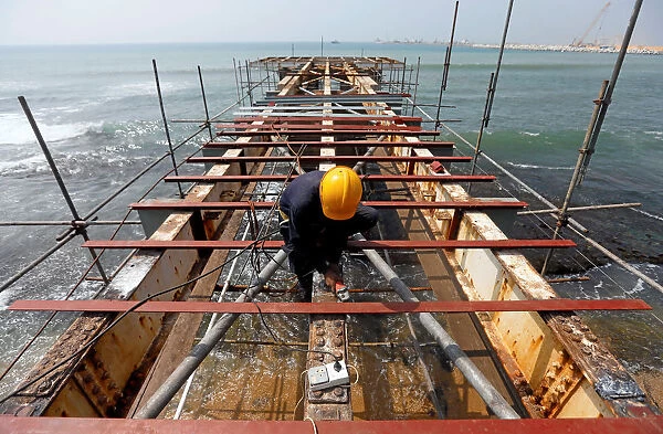 A labourer works at a construction site of a bridge on the sea in Colombo