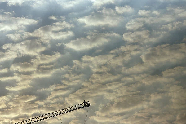 Labourers work on the edge of a ladder during the construction of a building in Mumbai