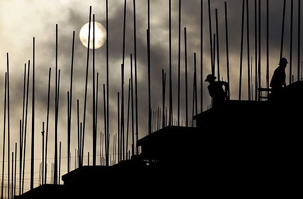 Labourers work during sunrise at a construction site of a residential complex in Puer
