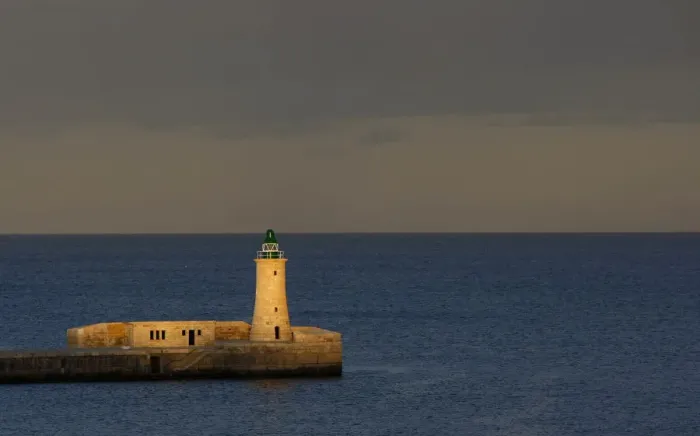 Framed Print : A lighthouse is seen at dusk in a harbour in Valletta
