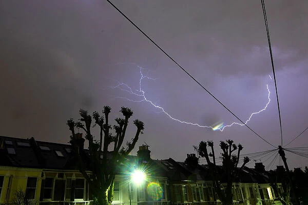 Lightning is seen from a bedroom window as it strikes above a street in south London