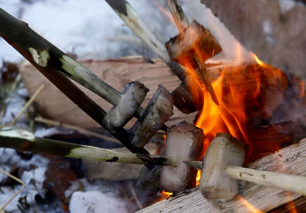 Local residents put pig fat in a camp fire during the celebrations of Kolyada pagan