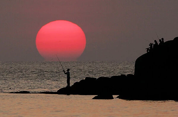 A local Thai man fishes at sunset near Patong Beach on the Thai resort island of Phuket