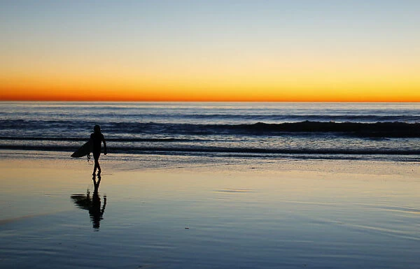 A lone surfer heads home after surfing past sunset in Leucadia