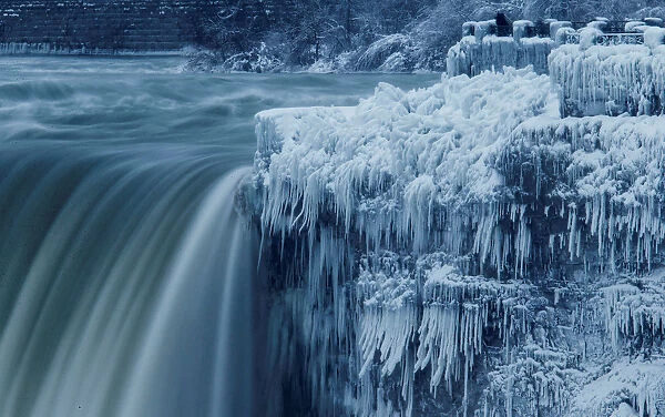 A lone visitor takes a picture near the brink of the ice covered Horseshoe Falls in