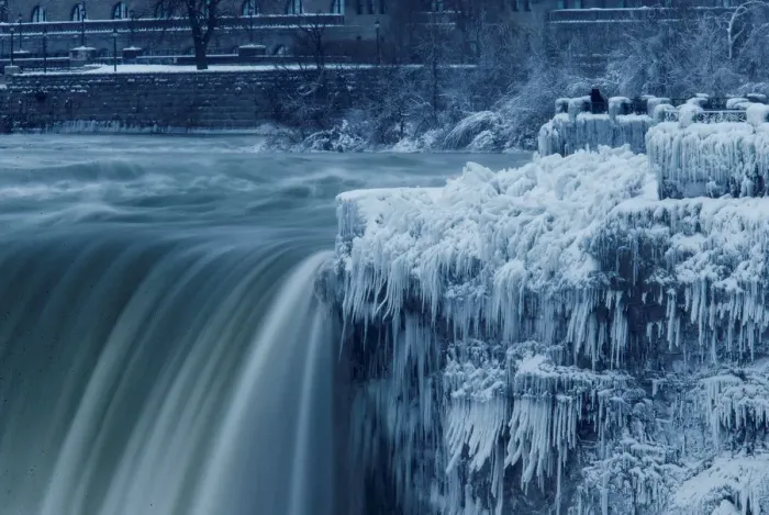 Framed Print : A lone visitor takes a picture near the brink of the ice covered Horseshoe Falls in