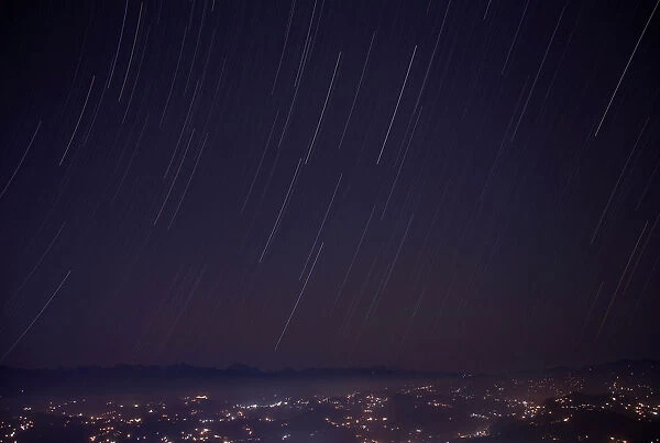 A long exposure picture shows a star trail above the mountain range during the Geminids