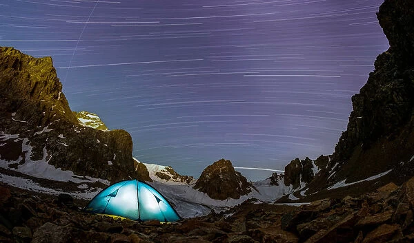 A long exposure picture shows stars and meteor trails above the mountains of Tien Shan