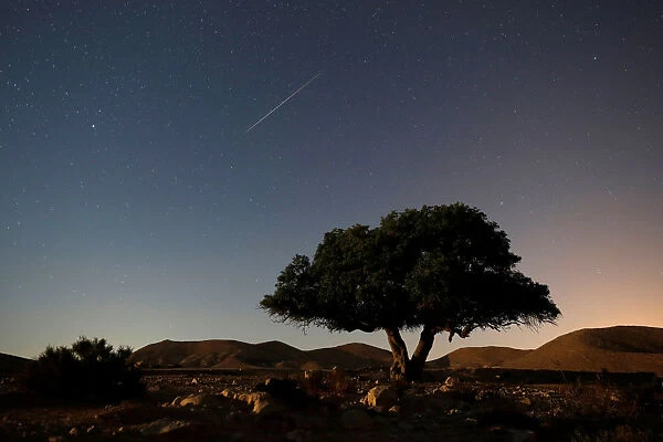A long exposure shows a meteor streaking across the sky in the early morning during the