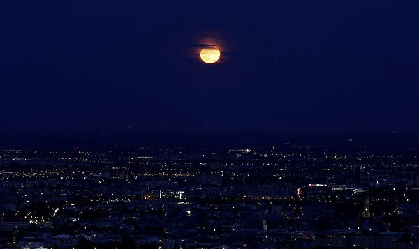 A long time exposure shows the moon over the city of Vienna