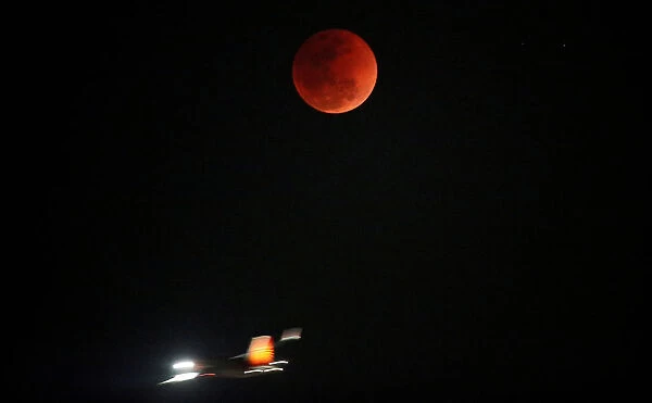 A lunar eclipse of a full Blue Moon is seen as an airplane passes by in Ahmedabad