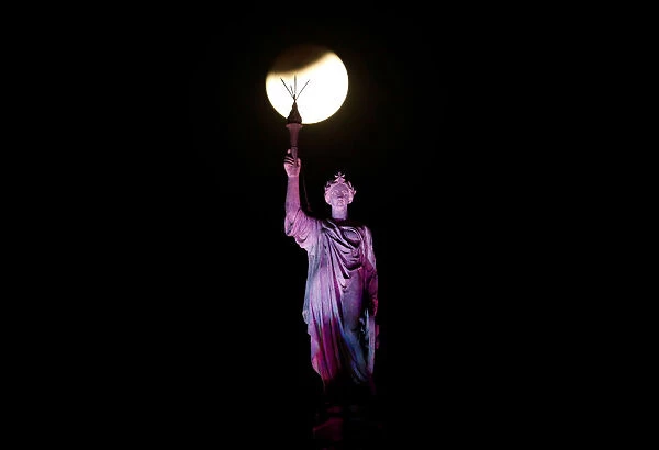 A lunar eclipse of a full Blue Moon is seen above a statue at the Chhatrapati Shivaji