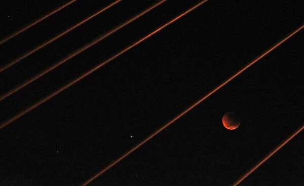 A lunar eclipse is visible among cables on the Anzac Bridge in Sydney