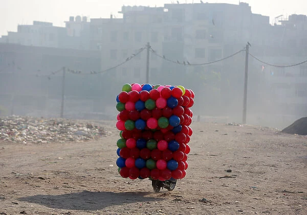 A man carries childrens coloured plastic balls on his motorcycle in Delhi