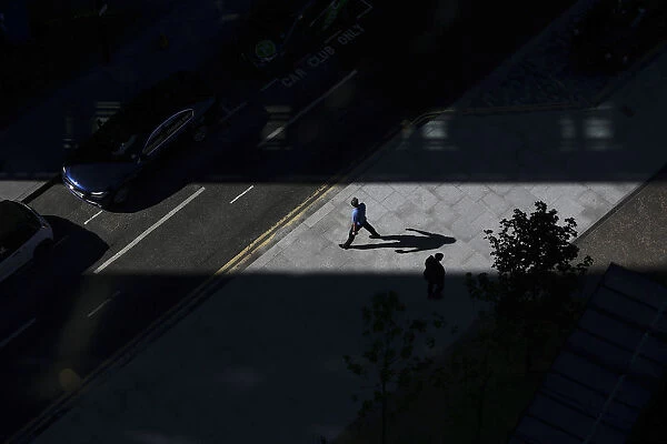 A man casts a shadow as he walks through a shaft of sunlight in London