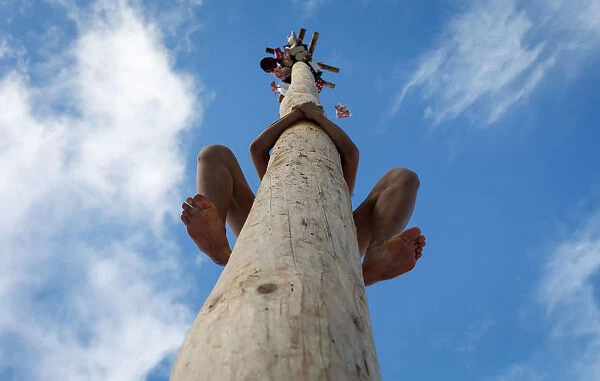 A man climbs up a wooden pole to get a prize during celebration of Maslenitsa