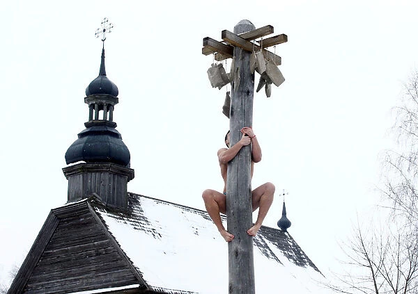 Man climbs up a wooden pole to get a prize during celebration of Maslenitsa