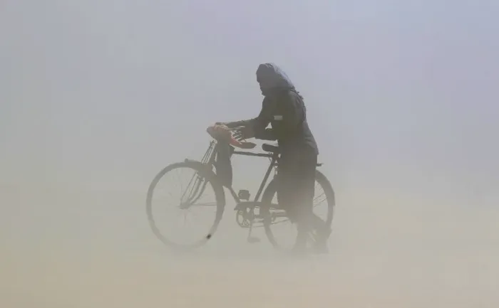 Framed Print : A man covers his face as he pushes a bicycle through a dust storm on the banks of Framed Print : A man covers his face as he pushes a bicycle through a dust storm on the banks of
