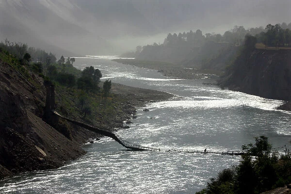 A man crosses over the Neelum River on a collapsed bridge at the Neelum Valley outside