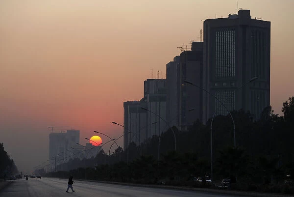 A man crosses a road as the sun sets in Islamabad