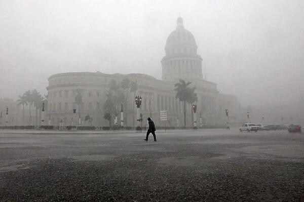 A man crosses the street during thunderstorms in Havana
