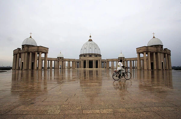 A man cycles past in front of the Basilica of Our Lady of Peace of Yamoussokro, a