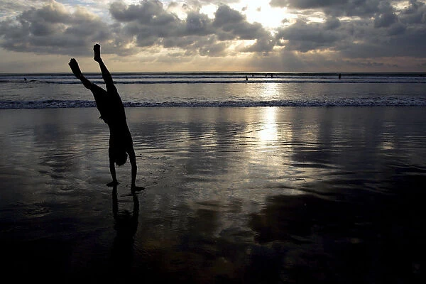 A man does a handstand on Kuta beach on the Indonesian resort island of Bali