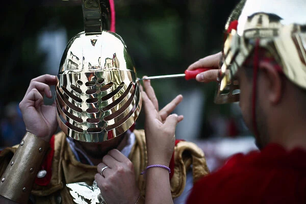 A man dressed as ancient Roman adjusts his helmet before a procession as part of Holy