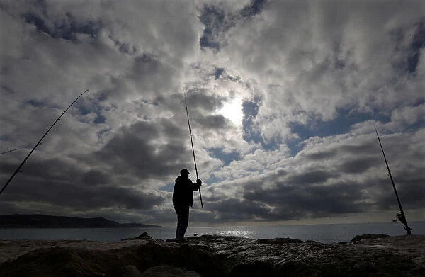 A man fishes on the beach of the Promenade des Anglais in Nice