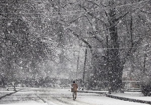 A man holding an umbrella walks during snowfall in Srinagar