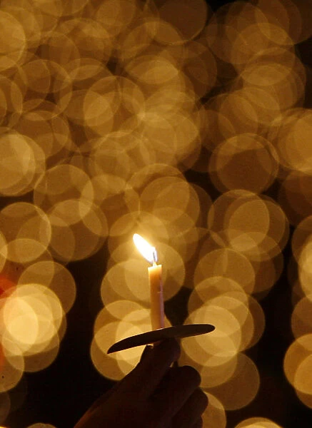 A man holds a candle during a Christmas mass at the Gelora Bung Karno stadium in Jakarta