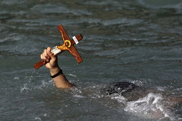 A man holds a cross after a competition to retrieve it from the water during Epiphany day