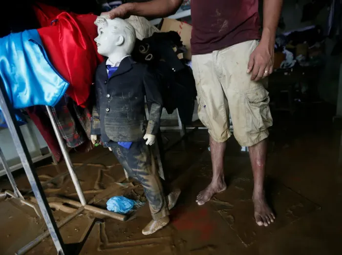 Framed Print : A man holds a muddied mannequin inside his tailoring shop, which was affected by floods Framed Print : A man holds a muddied mannequin inside his tailoring shop, which was affected by floods