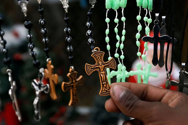 Man holds a religious locket displayed at a stall in a Christian neighbourhood in