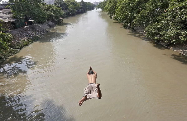 A man jumps into Tollys Nullah to cool off on a hot day in Kolkata