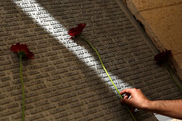 A man lays a flower on a monument engraved with names of victims of the September 11th