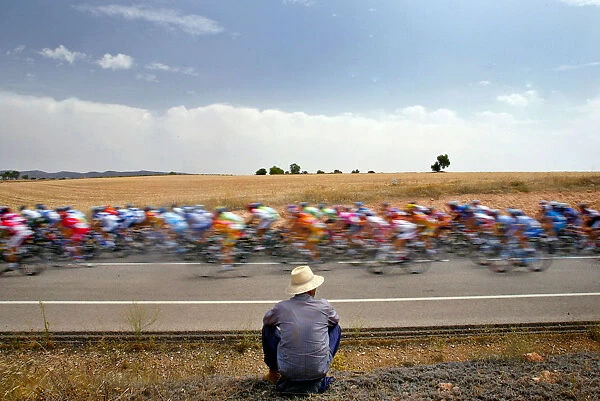 A man looks at a pack of riders cycle during the fifth stage of the Tour of Spain