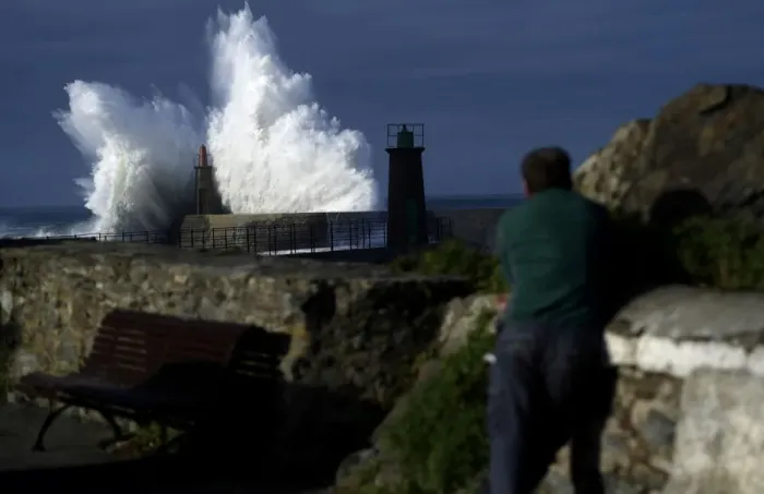 Framed Print : A man looks at waves as they crash against a lighthouse in the port town of Viavelez Framed Print : A man looks at waves as they crash against a lighthouse in the port town of Viavelez