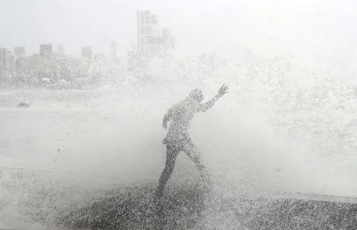 Framed Print : A man loses his balance as he gets drenched by a large wave during high tide at a