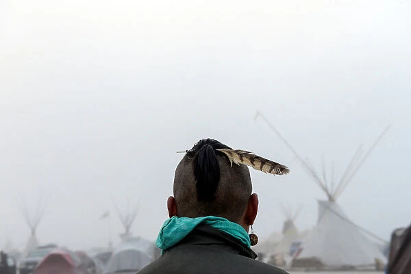 A man from the Muskogee tribe looks at the Oceti Sakowin shrouded in mist during a