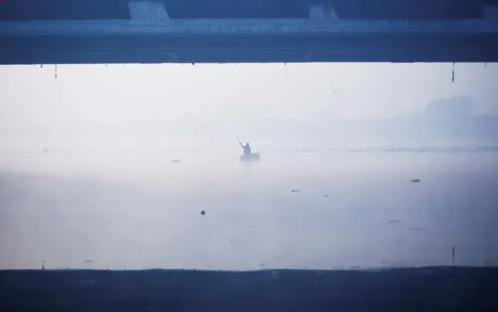 Framed Print : A man paddles a handmade boat across the Yamuna river on a foggy winter morning in New