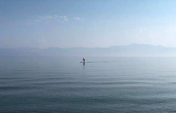 A man paddles in the Ionian Sea near the island of Corfu