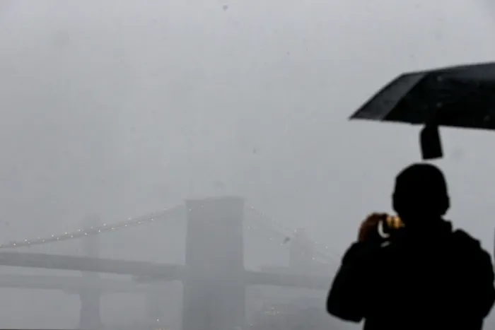 Framed Print : A man photographs the Brooklyn Bridge during a winter nor easter storm in New York Framed Print : A man photographs the Brooklyn Bridge during a winter nor easter storm in New York