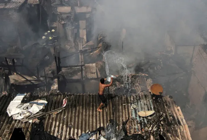 Framed Print : A man pours water to douse a fire that broke out in a slum in Mumbai Framed Print : A man pours water to douse a fire that broke out in a slum in Mumbai