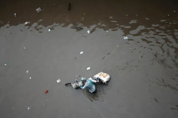 Framed Print : A man pushes his bicycle through a water-logged street after heavy rains in Ahmedabad