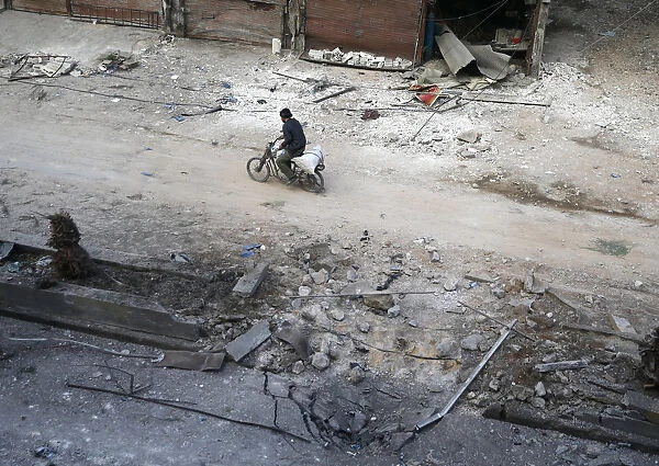 A man rides on a motorbike at a damaged site in the rebel held besieged town of