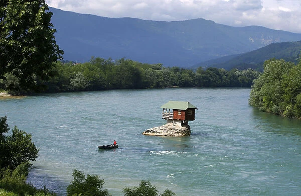 A man rows a boat near a tiny house build on a rock on the river Drina is seen near